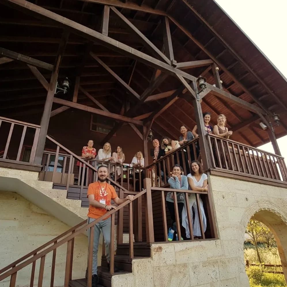 A group gathered on the wooden staircase and porch of a stone house
